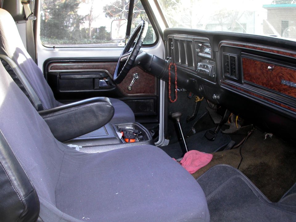 Blue cloth interior of a vintage Ford with woodgrain dash and floor shifter