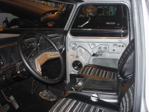1979 Ford Bronco - The interior of a 1979 Ford Bronco is visible, with a black vehicle in the background.