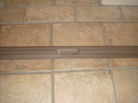 1996 Ford Bronco - A tan cargo cover with the name "BRONCO" embossed on its handle is shown against a tiled background.