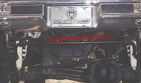 1986 Ford Bronco - Underside front view of a vehicle showing chrome front bumper with a license plate, front suspension components including coil springs and…