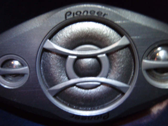 Close-up of a Pioneer oval coaxial car speaker with curved grille bars and side tweeters