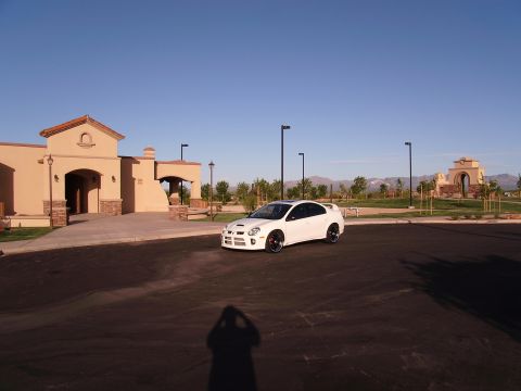1996 Ford Probe - A white Dodge Neon SRT-4 is parked in front of a tan building under a clear blue sky.