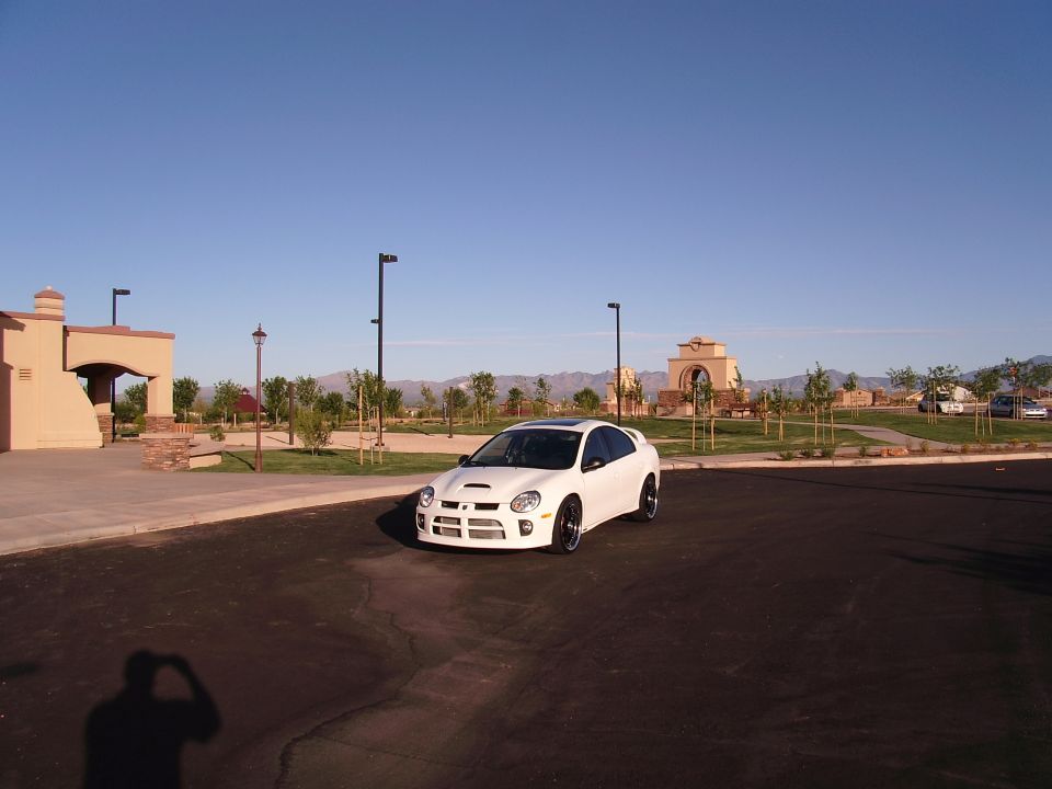 White Dodge Neon SRT-4 with a hood scoop and black rims parked on asphalt