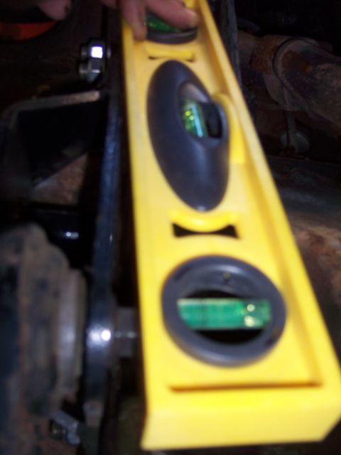 1996 Ford Bronco - A yellow bubble level is used to check the alignment of a vehicle's suspension component.