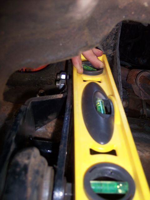 1996 Ford Bronco - A yellow level tool is used to check the alignment of a vehicle's undercarriage components.