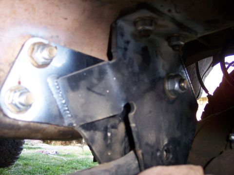 1996 Ford Bronco - Close-up view of a frame bracket with bolts and welds, with a portion of a tire visible.