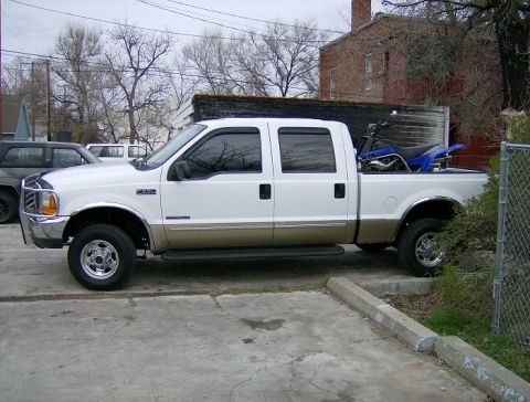 2000 Ford F-250 - This 2000 Ford F-250 crew cab pickup truck is seen from the side, carrying a blue dirt bike in its bed.
