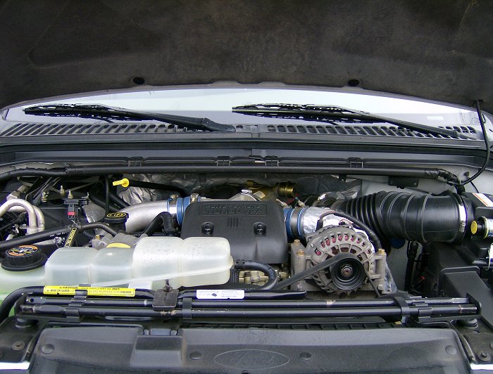 2000 Ford F-250 engine bay with a large black air intake hose, alternator, and coolant reservoir