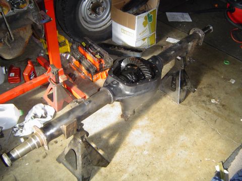 1978 Ford Bronco - A rear axle assembly, likely from a truck or SUV, is shown disassembled and supported by jack stands in a garage setting.