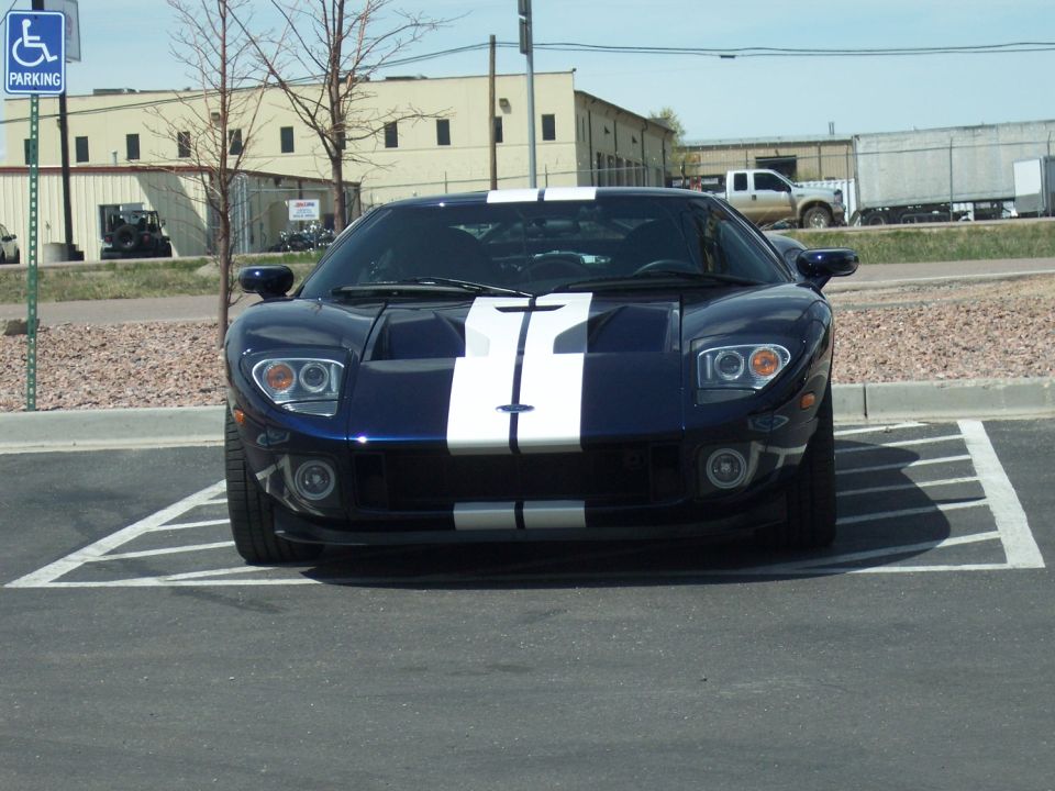 Dark blue sports car with white racing stripes parked in a handicapped spot