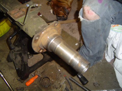 1978 Ford Bronco - A person works on a vehicle's axle component, which is supported by a jack stand in a garage setting.
