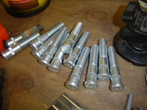 1978 Ford Bronco - Several lug bolts are scattered on a workbench, with a yellow can and black tool in the background.