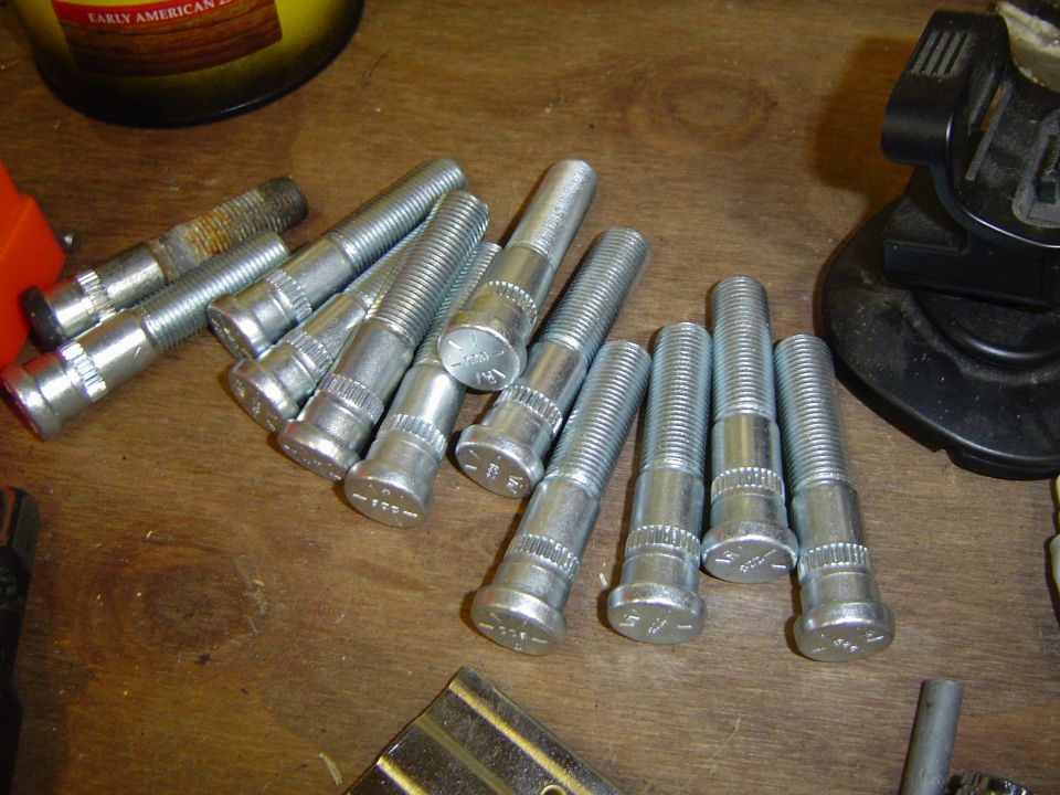 Extended zinc-plated wheel studs with knurled shanks on a workbench