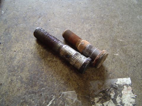 1978 Ford Bronco - Two lug bolts, one plated and one rusted, are shown on a concrete floor.