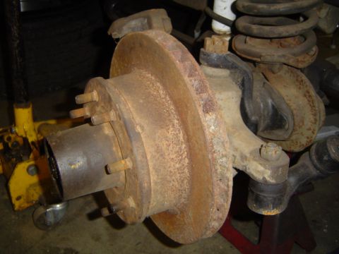 1978 Ford Bronco - A heavily rusted brake rotor and hub assembly is shown, with visible lug studs and suspension components.