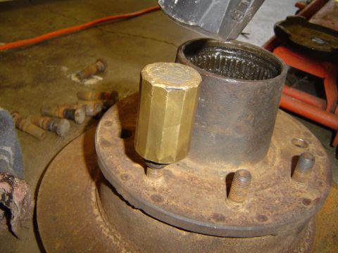 1978 Ford Bronco - A brass tool is used to tap a metal sleeve onto a vehicle's hub assembly.
