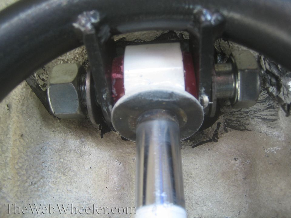 close-up of a suspension shock mount with red and white bushings and large nuts