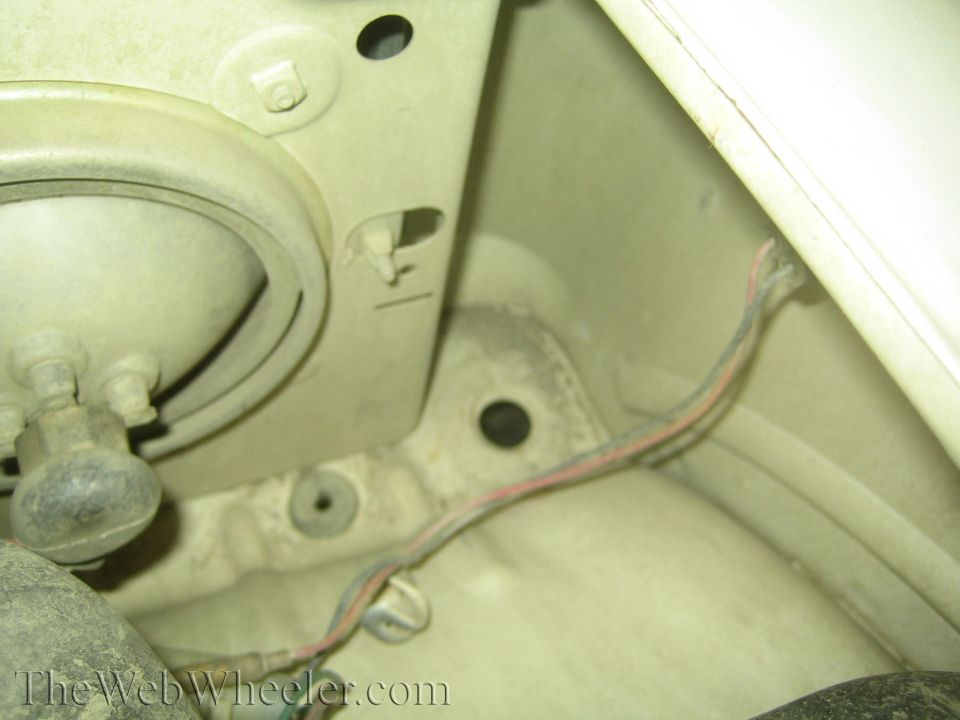 close-up of a vehicle's inner fender area, showing wiring and mounting points