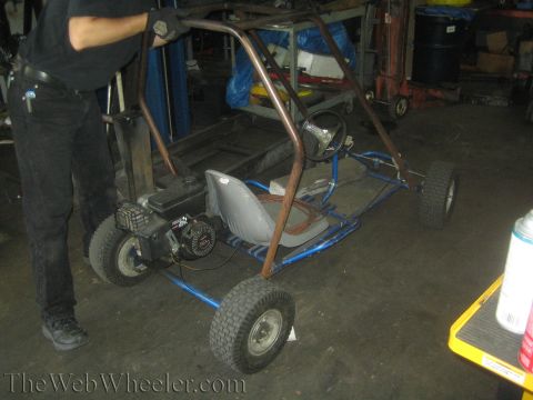 1987 Suzuki Samurai - A go-kart with a roll cage and a small engine is being worked on in a garage.