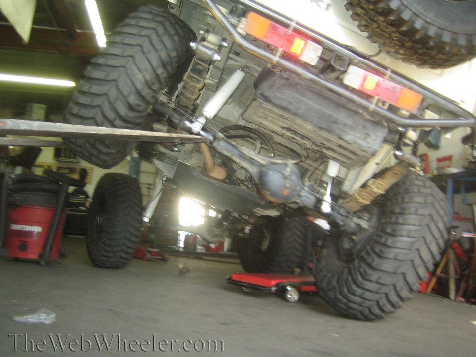 Undercarriage of a 1987 Suzuki Samurai with large off-road tires and suspension modifications