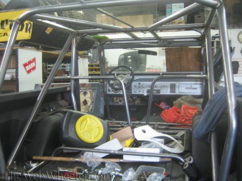 1987 Suzuki Samurai - The interior of a vehicle is shown, modified with a prominent roll cage and various parts.