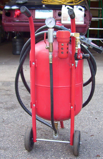 1965 Ford Mustang - A red sandblaster is positioned in front of a car body, suggesting a workshop or garage setting.