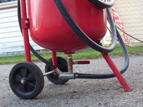 1965 Ford Mustang - A red sandblaster tank is shown with its wheels and hoses, a SuperMotors.net watermark.