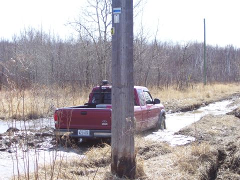 1996 Ford Bronco - A red pickup truck navigates a challenging muddy terrain with a visible license plate.