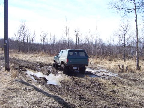 1996 Ford Bronco - 1996 Ford Bronco navigates a challenging muddy off-road path.