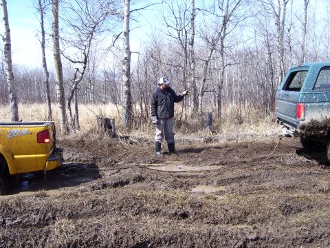 1996 Ford Bronco - Two vehicles are stuck in a muddy, wooded area, with one being pulled by the other.