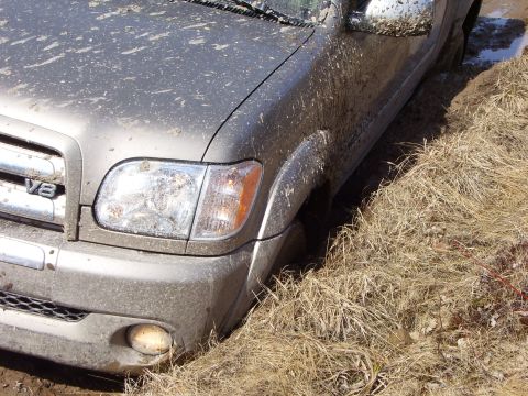 1996 Ford Bronco - Mud-splattered Toyota Tundra with V8 badge stuck in a grassy ditch.