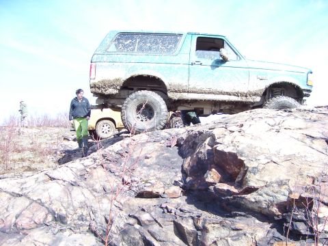 1996 Ford Bronco - A 1996 Ford Bronco navigates a challenging rocky trail, with another vehicle partially visible.