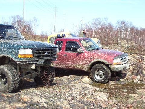 1996 Ford Bronco - Mud-splattered 1995 Ford F-150 is seen from the front, parked off-road with other vehicles.