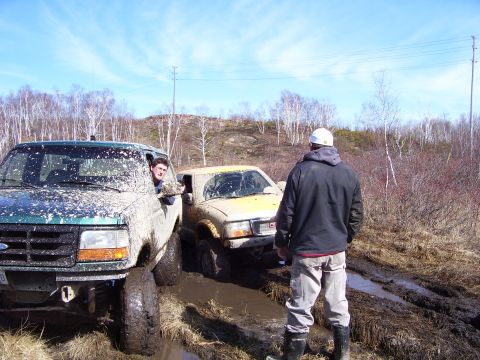 1996 Ford Bronco - A 1996 Ford Bronco and a yellow SUV are stuck in the mud during an off-road excursion.
