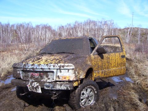 1996 Ford Bronco - This GMC pickup truck is heavily covered in mud after getting stuck in a wet, wooded area.