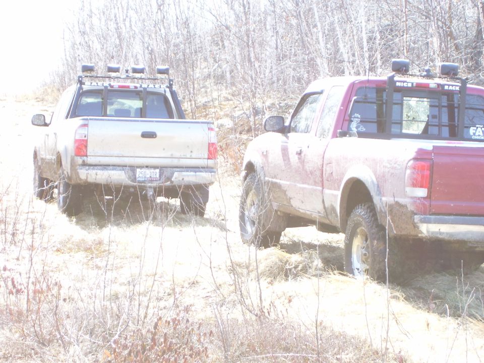 Rear view of two pickup trucks off-road, one red and one silver