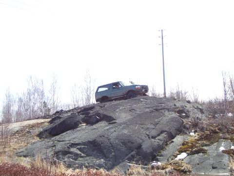 1996 Ford Bronco - 1996 Ford Bronco positioned on a rocky outcrop under a bright sky.