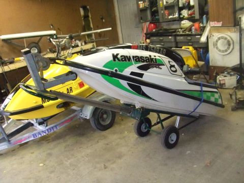 1995 Ford Mustang - Two jet skis, a white Kawasaki and a yellow Bandit, are parked on trailers in a garage.