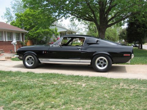 1968 Shelby GT500 - A black 1968 Shelby GT500KR is parked on a concrete driveway in a suburban setting.