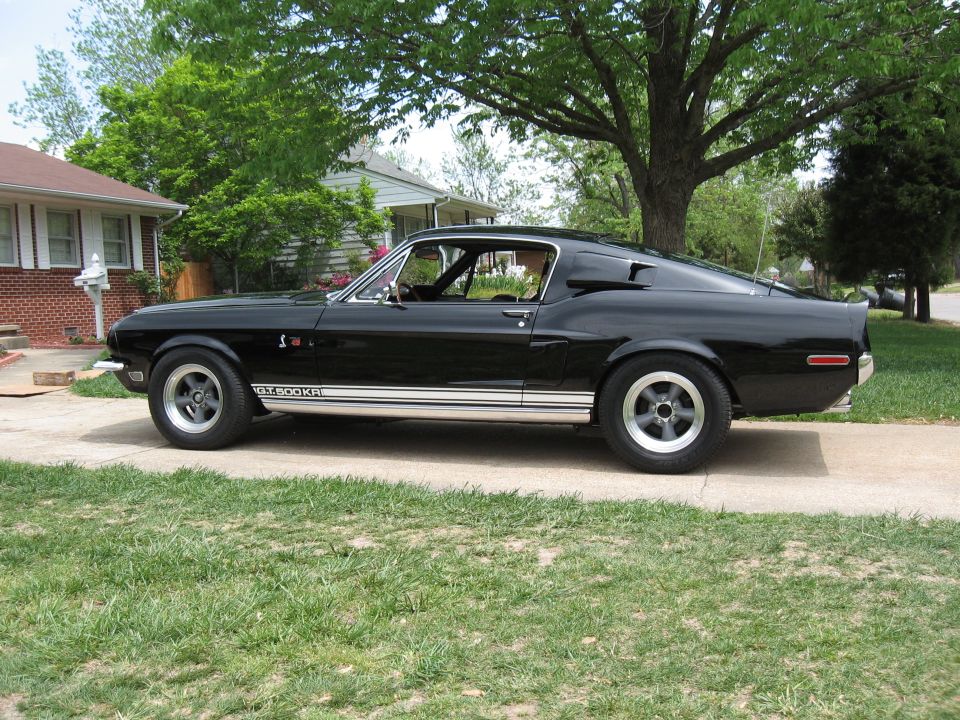 Black 1968 Shelby GT500KR parked on a driveway in front of a house