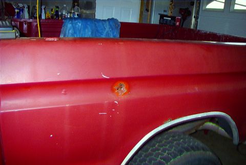 1979 Ford F-150 - Close-up of a red pickup truck's side, showing a rust patch and minor damage.