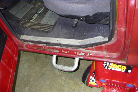 1979 Ford F-150 - Close-up of a truck's interior door sill and floor mat, with a toy Jeep visible below.