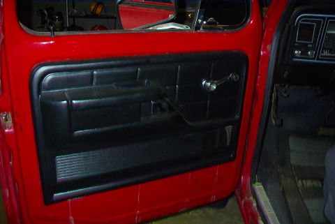 1979 Ford F-150 - Interior view of a red 1979 Ford F-150, showing the driver's side door panel and dashboard.