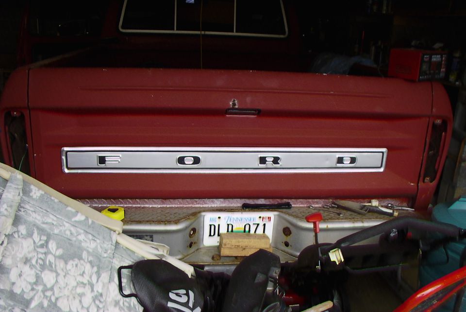 Red Ford pickup tailgate with chrome FORD lettering and Tennessee plate in a garage