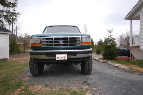 1996 Ford Bronco - Front view of a green Ford truck with a prominent grille and aftermarket tires.