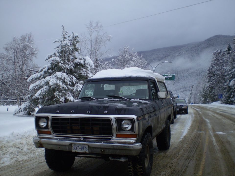 Black 1978 Ford Bronco with snow on roof, parked on a snowy road