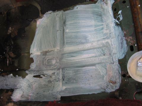 1973 Ford Ranchero - A section of a vehicle's floor pan is covered in white sealant, obscuring its original condition and details.