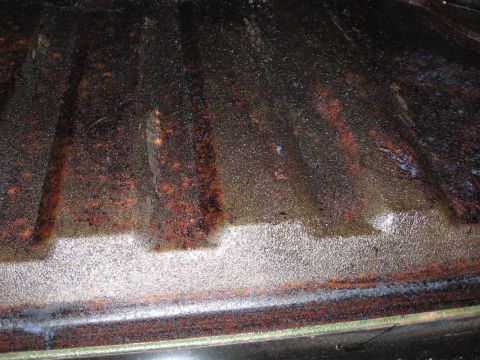 1973 Ford Ranchero - The ribbed surface of a truck bed floor shows significant rust and some white residue along the edge.
