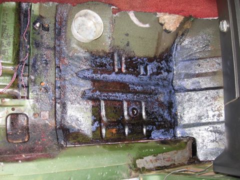 1973 Ford Ranchero - The interior floor of a vehicle shows significant rust and staining, with some wiring visible.