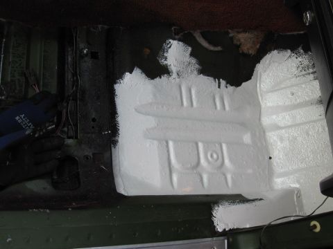 1973 Ford Ranchero - A person in gloves works on repairing the floor of a vehicle, applying white paint to the metal.